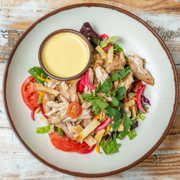 Guapo's GO chicken salad with tomatoes, pickled onions, tortilla strips, and a side of dressing.