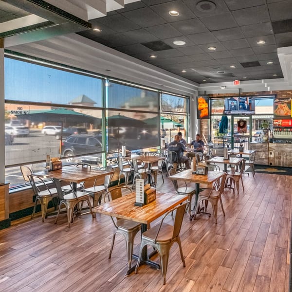 Interior of Guapo's GO with wooden tables, metal chairs, large windows, and a few patrons.