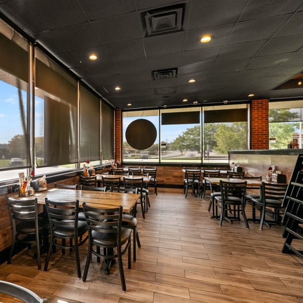 Interior of Guapo's GO with wooden tables, black chairs, and large windows with shades.
