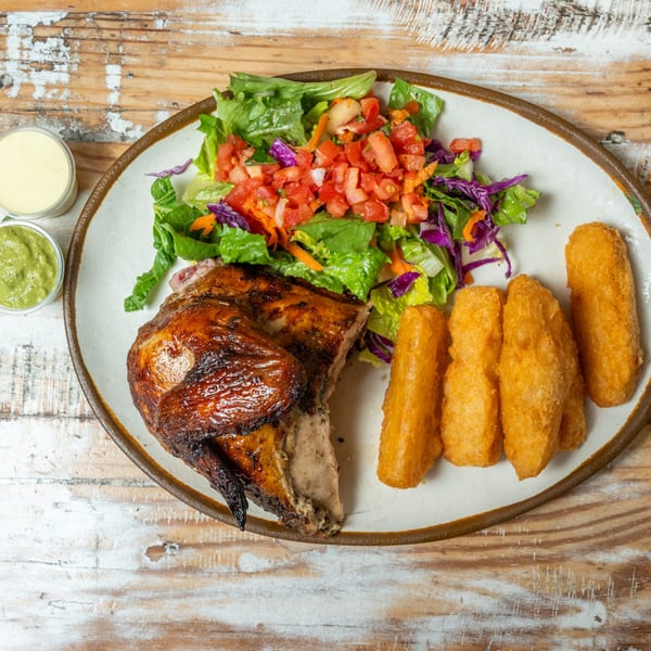 Guapo's GO charcoal chicken with a side salad, fried plantains, and two dipping sauces.
