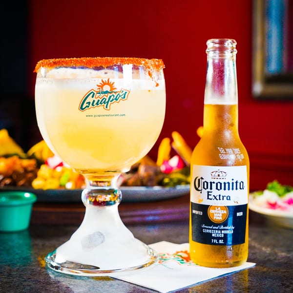 A Guapo's margarita with a chili-lime rim next to a Coronita beer bottle.