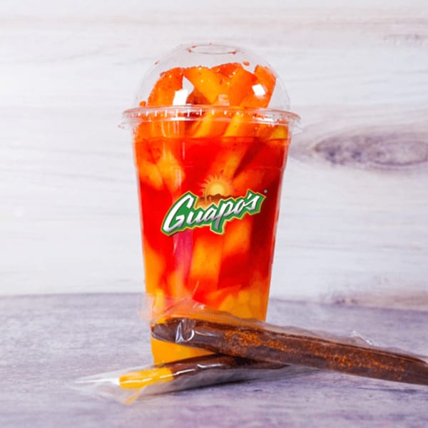 Guapo's mango chamoy drink with fresh mango chunks and two tamarind candy straws.