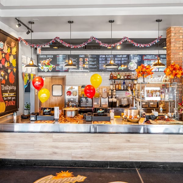 Guapo's GO counter with menu boards, Thanksgiving decor, and food preparation area.
