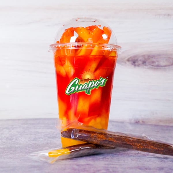 Guapo's mango drink with chili powder and two tamarind candy straws on a light background.