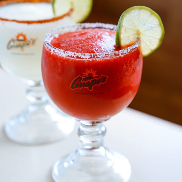 Two Guapo's margaritas, one red strawberry and one white, both garnished with lime and salt.