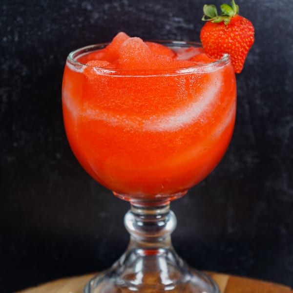 A vibrant red frozen strawberry margarita in a glass, garnished with a fresh strawberry.